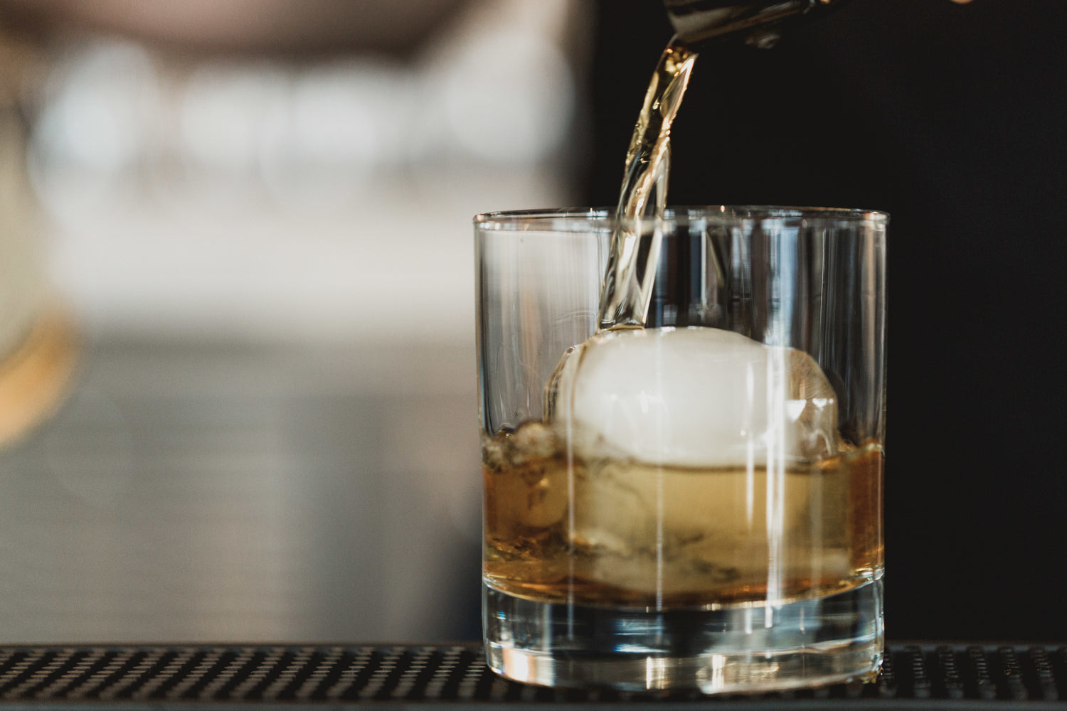 brown liquor being poured into a glass at a bar